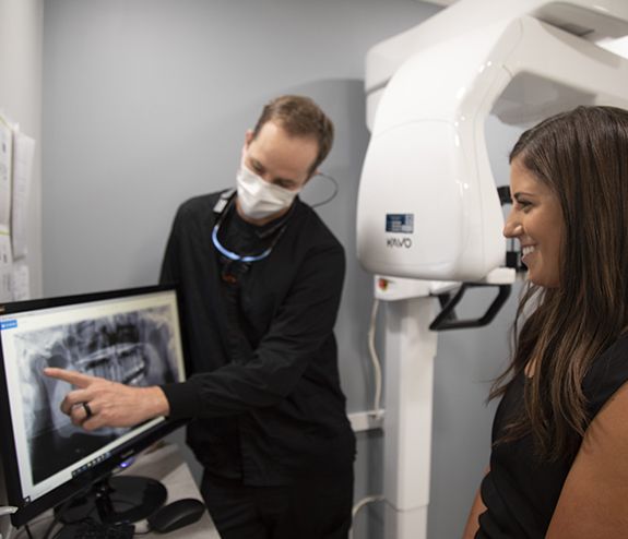 Dentist pointing to dental x-rays talking to patient
